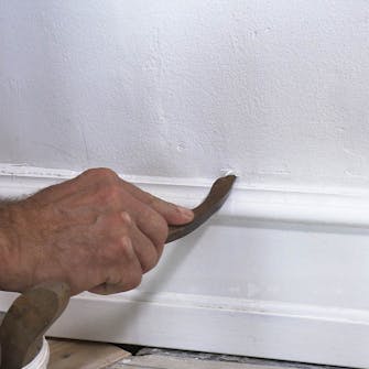 Iso rako seinän ja jalkalistan välissä: Vedä massa tasaiseksi saumaustikulla Iso rako seinän ja jalkalistan välissä: Vedä massa tasaiseksi saumaustikulla